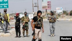 Sunni fighters who have joined Shi'ite militia groups known collectively as Hashid Shaabi (Popular Mobilization), allied with Iraqi forces against the Islamic State group, carry weapons as they stand guard in al-Alam Salahuddin province, March 15, 2015.