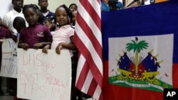 ARCHIVO - Niños parados junto a banderas de EEUU y Haití mientras sostienen carteles en apoyo de la renovación del TPS para inmigrantes de Centroamérica y Haití que ahora viven en Estados Unidos, durante una conferencia de prensa el lunes 6 de noviembre de 2017 en Miami.