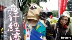 Seorang peserta aksi demo Hari Buruh (May Day) menggunakan topi kuda dan rantai dalam pawai yang melintasi gedung Eksekutif Yuan di pusat kota Taipei, Taiwan (1/5).