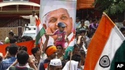 A supporter of anti-corruption activist Anna Hazare, portrait seen, carries a child on his head as he waits along with others outside Tihar prison, where Hazare is presently lodged, in New Delhi, India, August 18, 2011