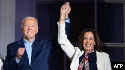 El presidente Joe Biden y la vicepresidenta Kamala Harris se toman de la mano y hacen gestos mientras miran el espectáculo de fuegos artificiales del Día de la Independencia desde el Balcón Truman de la Casa Blanca en Washington, DC, el 4 de julio de 2024.