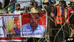 Sudanese protesters rally in front of a court in Omdurman near the capital Khartoum, Dec. 30, 2019, during the trial of intelligence agents for the death of teacher Ahmed Al-Khair, portrait at right, while in custody of intelligence services. 