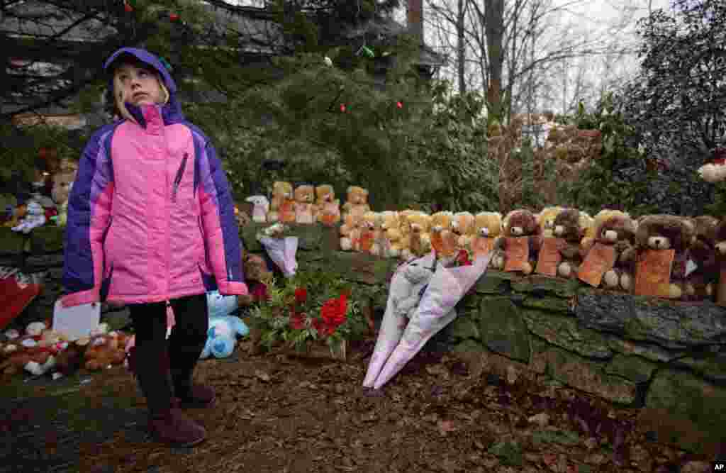 Ava Staiti, 7, of New Milford, Conn., looks up at her mother Emily Staiti, not pictured, while visiting a sidewalk memorial with 26 teddy bears, each representing a victim of the Sandy Hook Elementary School shooting, December 16, 2012, in Newtown, Connecticut.