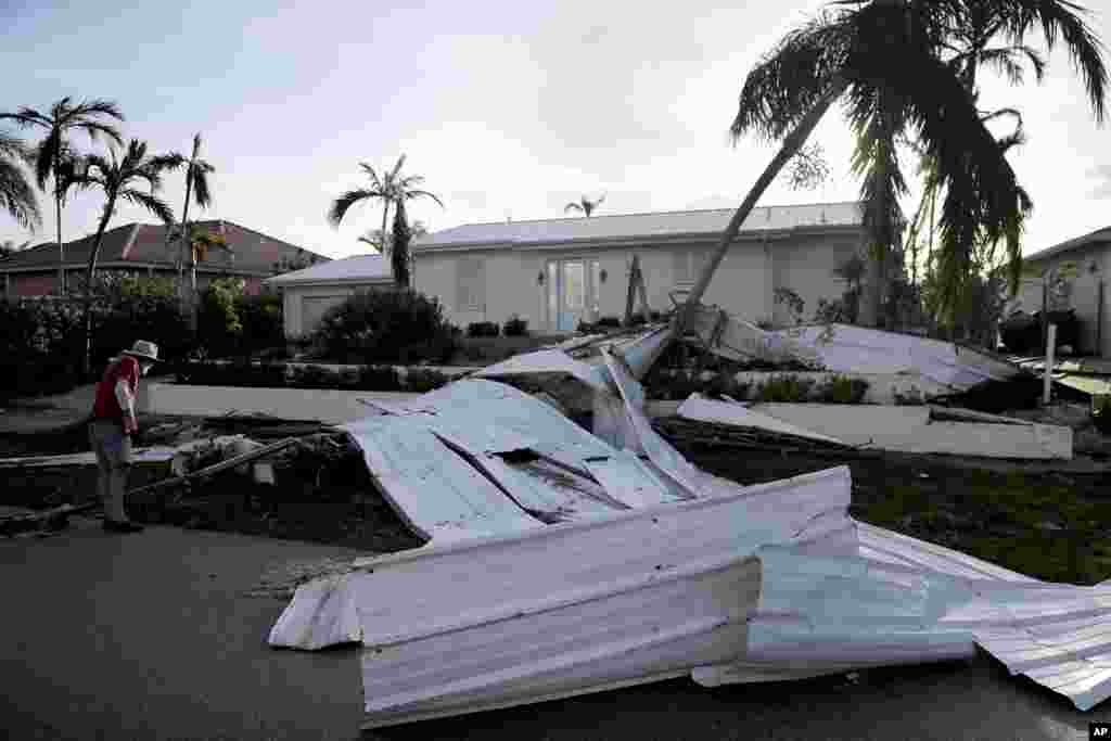 A roof is strewn across a home&#39;s lawn as Rick Freedman checks his neighbor&#39;s damage from Hurricane Irma in Marco Island, Florida, Sept. 11, 2017.