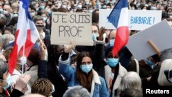 Orang-orang berkumpul di Place de la Republique di Paris, untuk memberi penghormatan kepada Samuel Paty, guru yang dipenggal di Conflans-Sainte-Honorine, Perancis, 18 Oktober 2020. Poster itu bertulisan "Saya Guru." (Reuters)