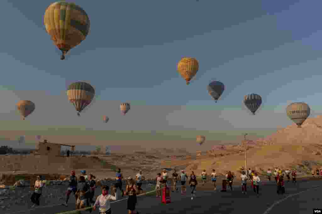 Against the backdrop of the Temple of Hatshepsut, hot-air balloons rise above runners in Luxor’s 32nd Egypt International Marathon. Organizers say the event attracted 430 participants from 45 countries this year. (Hamada Elrasam/VOA) 