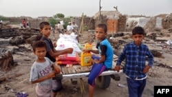 FILE - Internally displaced Yemenis whose camp was ravaged by fire two days earlier receive food aid in the village of al-Durayhimi, on the southern edge of the flashpoint Red Sea port city of Hodeida, July 19, 2021. 