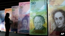 Seorang perempuan melihat versi besar mata uang Venezuela baru, yang disebut 'Strong Bolivar' di Caracas pada 2013, sebagai ilustrasi. (Foto: AP)