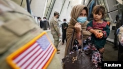 FILE - Afghan refugees board a bus taking them to a processing center upon their arrival at Dulles International Airport in Dulles, Virginia, September 1, 2021. 