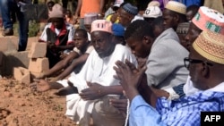 Des hommes prient près d'une tombe dans un cimetière de la capitale régionale Ziguinchor, au sud du Sénégal, le 7 janvier 2018.