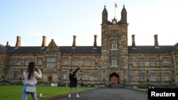 FILE - Two students from China take photos at the University of Sydney, in Sydney, Australia, Aug. 11, 2020.