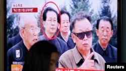 A woman walks past a video screen showing a report on Jang Song Thaek, the North Korean leader's uncle, at a railway station in Seoul, Dec. 3, 2013. 