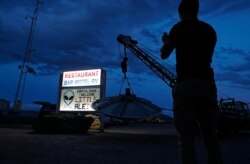 A man takes a picture of a sign at the Little A'Le'Inn during an event inspired by the "Storm Area 51" internet hoax, Sept. 19, 2019, in Rachel, Nev. Hundreds arrived in the desert after a Facebook post inviting people to "see them aliens."