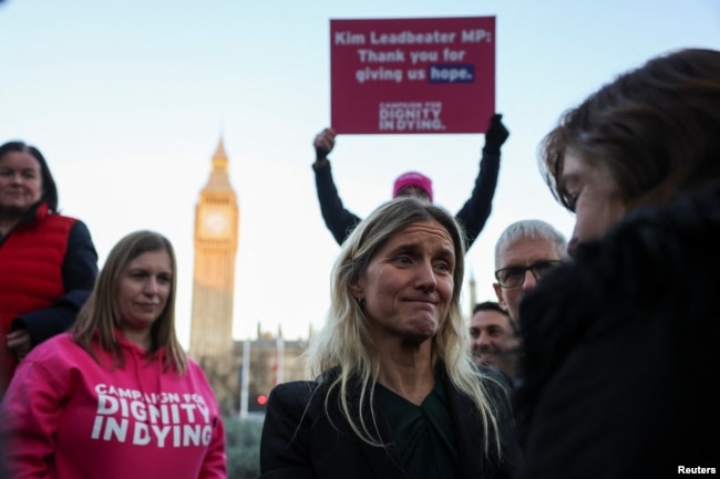 Para pengunjuk rasa menunjukkan plakat di depan Parlemen di London, Jumat, 29 November 2024 saat anggota parlemen Inggris memberikan persetujuan awal terhadap RUU Eutanasia. (Alberto Pezzali/AP)