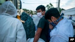 Guatemalans deported from the U.S., wearing a mask as a precaution against the spread of the new coronavirus, line up to board a bus after arriving at La Aurora airport in Guatemala City, June 9, 2020.