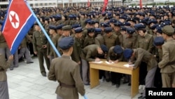 15일 북한의 비공개 장소에서 젊은 청년들이 군 입대 및 복귀 신청서에 서명하는 모습을 북한 관영매체 조선중앙통신이 보도했다.