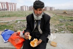 An Afghan migrant eats outside a bus terminal, as he and others struggle to find buses to take them to western Turkish cities, after crossing the Turkey-Iran border in April 11, 2018.