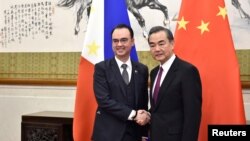 Menteri Luar Negeri Filipina Alan Peter Cayetano (kiri) berjabat tangan dengan Menlu China Wang Yi di Diaoyutai State Guesthouse, Beijing, China, 21 Maret 2018.