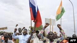 Supporters of Niger's National Council for the Safeguard of the Homeland (CNSP) hold a Niger flag (R) and a Russian flag (L) as they gather for a demonstration in Niamey on August 11, 2023 near a French airbase in Niger.