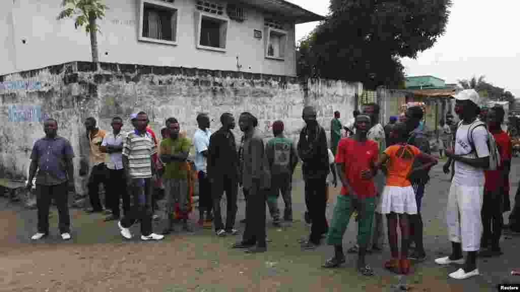 Residents gather to watch security forces patrol the street near state television headquarters in Kinshasa, Dec. 30, 2013. 