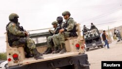 Members of the Mexican Army sit on the pickup truck near the scene where, according to local media, unknown assailants tried to set a bus on fire, in Ciudad Juarez.