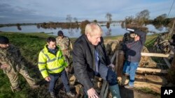 Britain's Prime Minister Boris Johnson climbs over a fence during a visit to see the effects of recent flooding, in Stainforth, England, Nov. 13, 2019. 