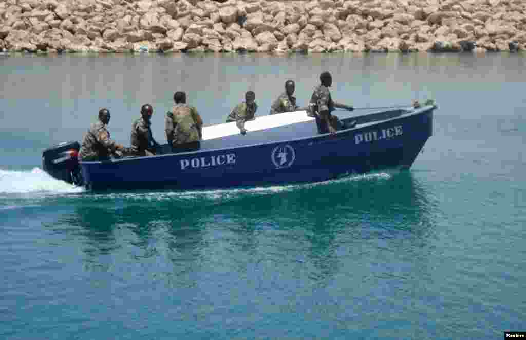 Anggota angkatan laut Puntland membawa peti putih berisi jenazah bajak laut Somalia yang dibunuh di Bossasso, April 2009.