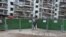 FILE - A man wearing a face mask keeps watch at an entrance to a residential community that has been fenced in with temporary barriers, in Yichang city of Hubei, the province hit hardest by the novel coronavirus outbreak, Feb. 10, 2020.