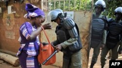 Un policier fouille le sac d'une femme devant un bureau de vote à Bamako, 20 novembre 2016.