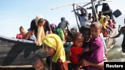 Anak-anak dibantu turun dari kapal kayu yang membawa pengungsi Rohingya dari Myanmar ke Pantai Shah Porir Dwip, di Teknaf, dekat Cox's Bazar, 1 Oktober 2017. 