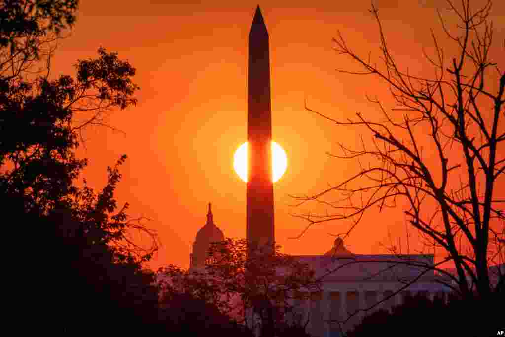 The sun rises behind the Washington Monument on the last day of summer in Washington, D.C.