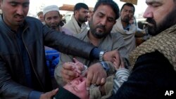 A health worker gives a polio vaccine to an Afghan refugee child in Peshawar, Pakistan, Feb. 18, 2020.