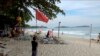 Seorang pria menancapkan tiang dengan bendera merah, yang mengindikasikan cuaca buruk di pantai Chaweng, Koh Samui, Thailand, Kamis, 3 Januari 2019.