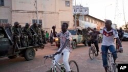 Warga bersorak saat pasukan Senegal mengambil posisi dekat gedung pemerintahan di Banjul, Gambia, sehari setelah pemimpin Gambia yang kalah, Yahya Jammeh, diasingkan (22/1). (AP/Jerome Delay)