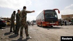 Syrian rebels and their families leave in a bus from a camp on the edge of Douma, April 9, 2018.