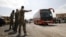 Syrian rebels and their families leave in a bus from a camp on the edge of Douma, April 9, 2018.