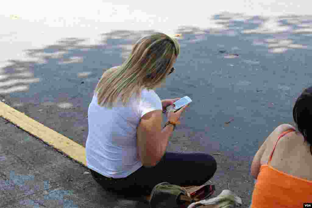 Una mujer env&iacute;a un texto despu&eacute;s de emitir su voto para elegir al nuevo presidente venezolano, el domingo 7 de octubre. [Foto: Iscar Blanco, VOA]