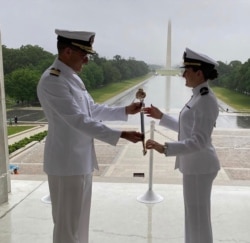 US Navy RDML (Sel.) Putnam Browne presents his daughter, Navy ENS Francesca Browne, with a family sword during her commissioning ceremony at the Lincoln Memorial. (Browne Family May 2020)