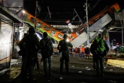 Soldados observan mientras los rescatistas trabajan en un sitio donde un paso elevado de un metro colapsó parcialmente con vagones de tren en la estación de Olivos en la Ciudad de México, México, el 4 de mayo de 2021.