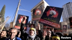 Demonstran Iran meneriakkan slogan sambil membawa foto ulama Syiah Sheikh Nimr al-Nimr saat demo menentang eksekusinya di Saudi Arabia, di luar Kedutaan Besar Arab Saudi di Teheran 3 Januari 2016.