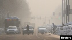 Pedestrians cross a road amid smog on a polluted day in Nanjing, Jiangsu province, China, Jan. 30, 2018.