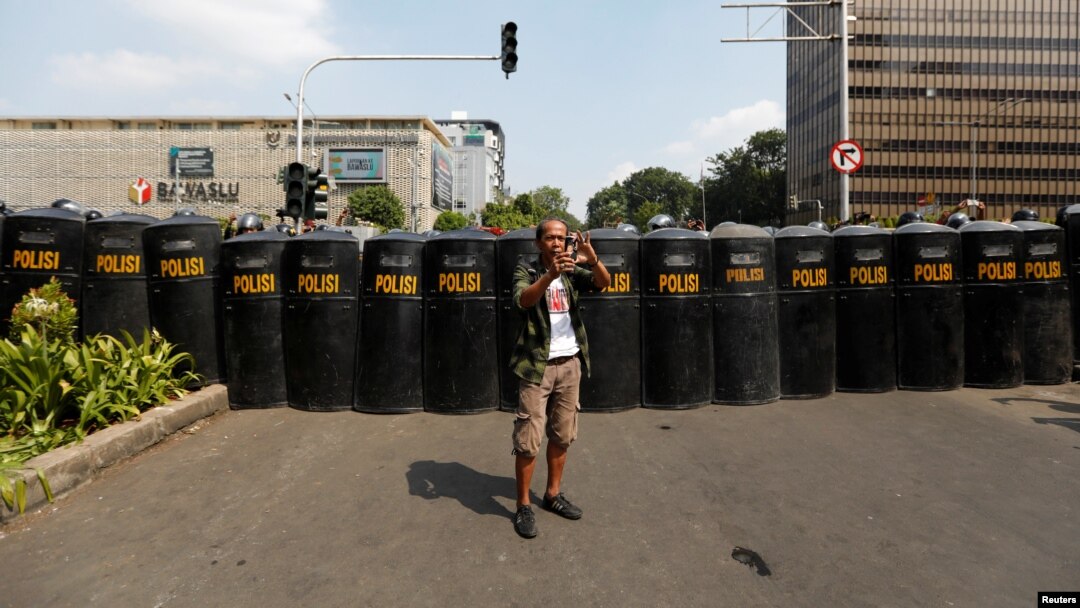 Seorang pria menggunakan ponsel dalam aksi massa menyusul penetapan hasil pilpres. Aksi masa berlangsung dekat kantor Badan Pengawas Pemilihan Umum (Bawaslu) di Jakarta, Indonesia, 22 Mei 2019. (Foto: Reuters/Willy Kurniawan)
