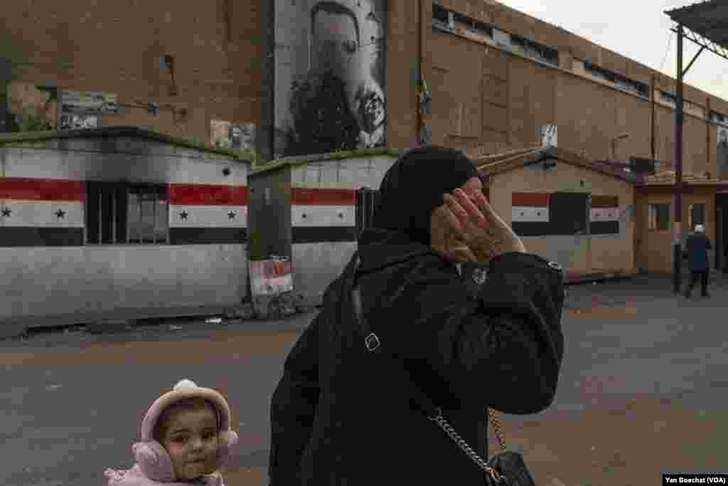 A woman hides her face near one of the many military bases surrounding the Yarmuk Palestinian refugee camp.