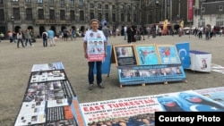 FILE - Abdurehim Gheni stands in demonstration with pictures of his relatives and other disappeared Uighurs, at Dam Square in Amsterdam in July. (Photo courtesy: Abdurehim Gheni)