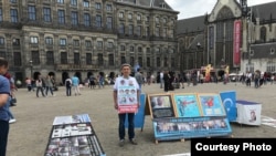 FILE - Abdurehim Gheni stands in demonstration with pictures of his relatives and other disappeared Uighurs, at Dam Square in Amsterdam in July. (Photo courtesy: Abdurehim Gheni)