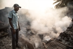 A man stands in front of a burnt-down house in the PK5 district in Bangui, Dec. 26, 2019