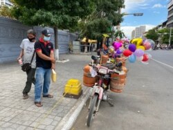 Soeung Tha sells balloons in front of Phnom Penh’s Lanka Temple, Dec. 7, 2020. (Aun Chhengpor/VOA Khmer)