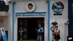 Turis berfoto di depan Gereja Maradona di San Andres Cholula, negara bagian Puebla, Meksiko, Minggu, 18 Juli 2021. (AP Photo/Marco Ugarte)