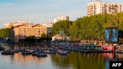 People attend the screening of the French movie 'Le grand bain' in the Bassin de la Villette on the first day of the 19th edition of the 'Paris Plages' (Paris Beaches) summer event on July 18, 2020, in Paris. 