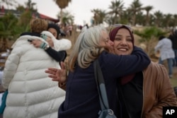 FILE —Palestinian and Israeli women activists from the Israeli Women Wage Peace movement and the Palestinian Women of the Sun movement, hug each other upon their arrival for the joint platform inauguration ceremony, at the Dead Sea, Jericho, Friday, March 25, 2022.